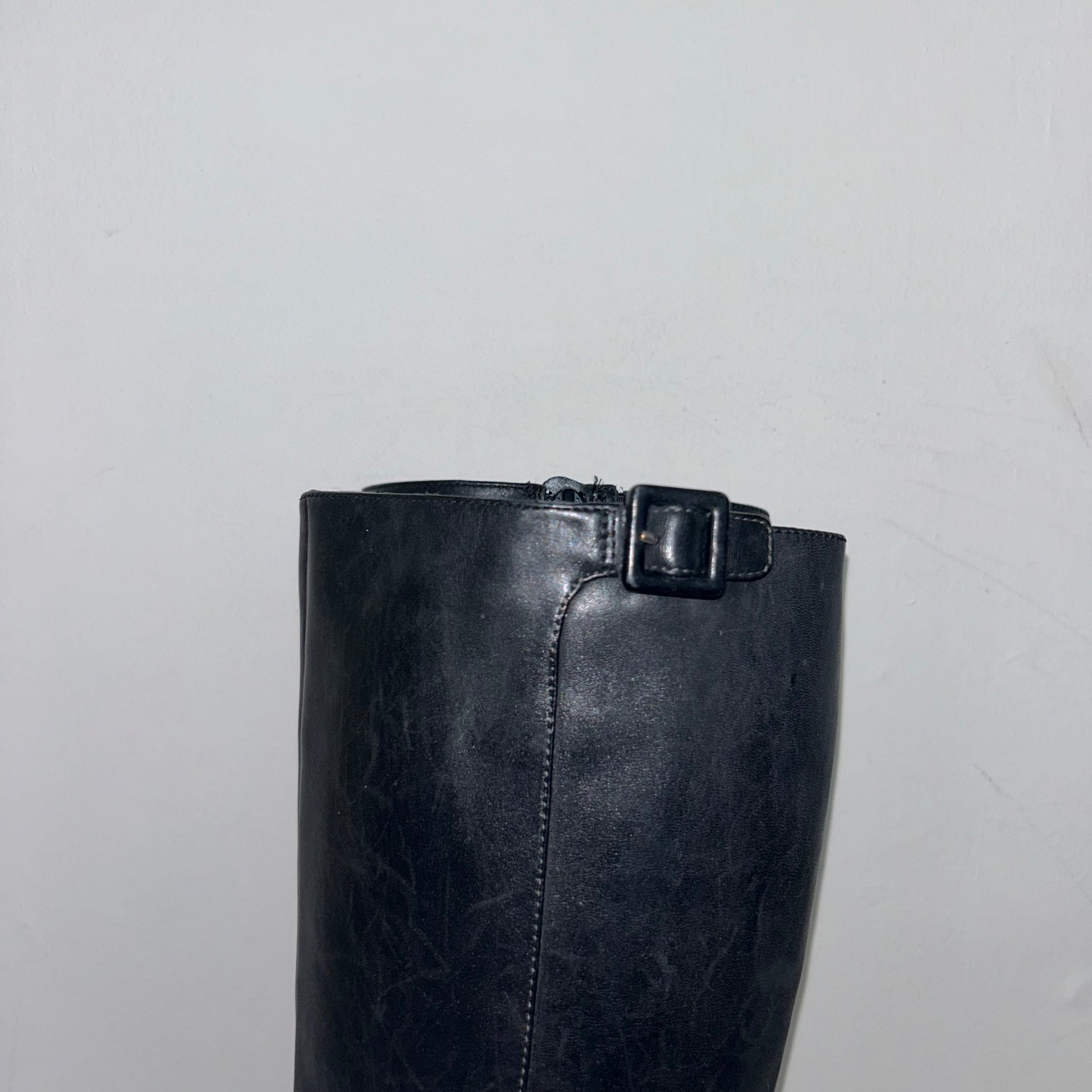 close up of black knee high boots shown on a white background