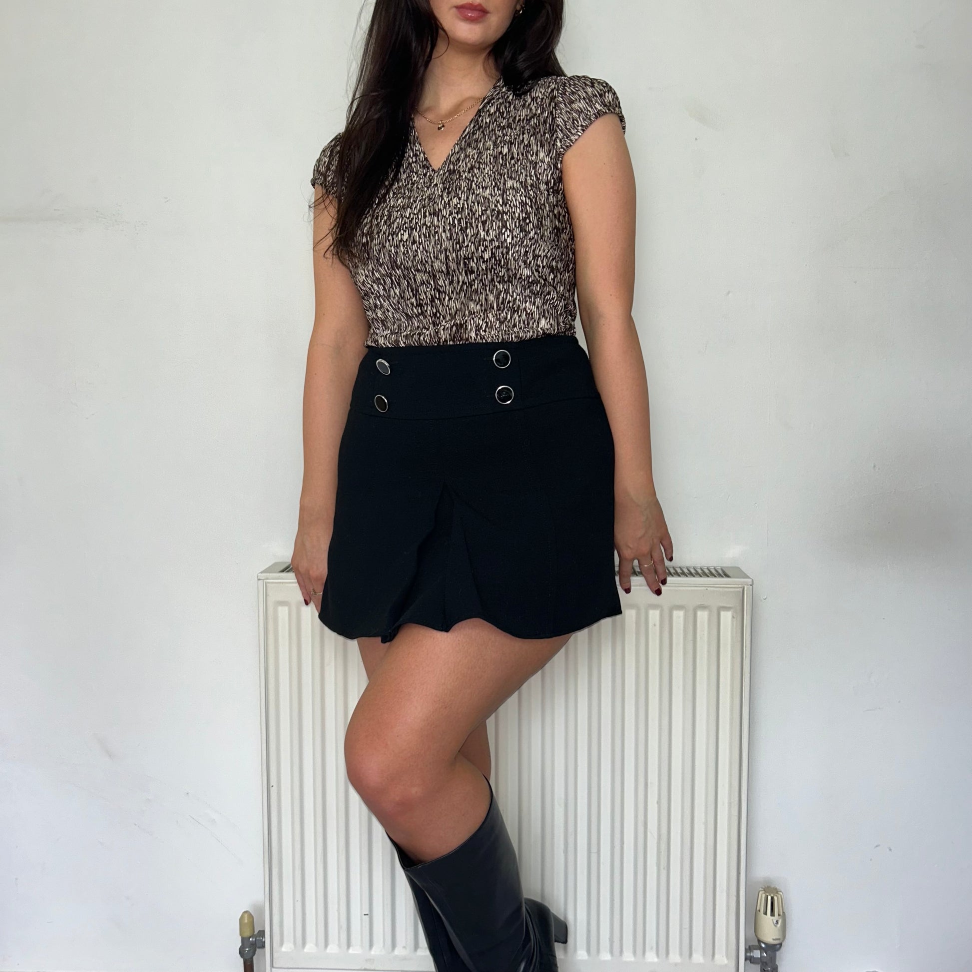 brown and beige short sleeve blouse shown on a model wearing a black mini skirt and black boots