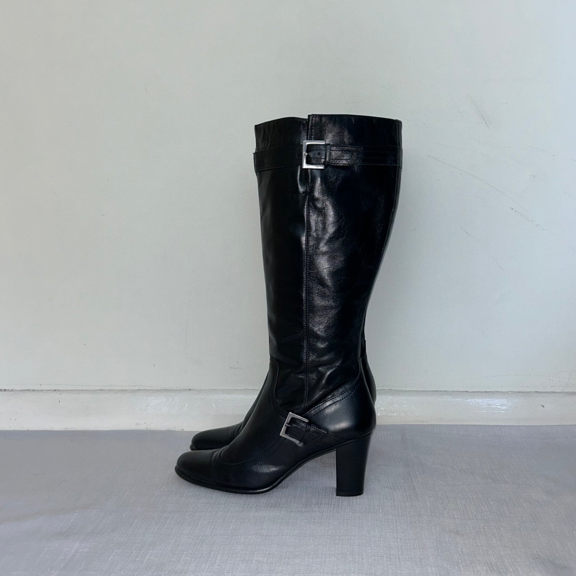 black knee high block heel leather boots shown on a white background