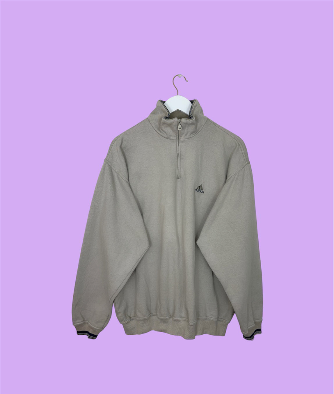beige 1/4 zip sweatshirt with small adidas logo shown on a lilac background