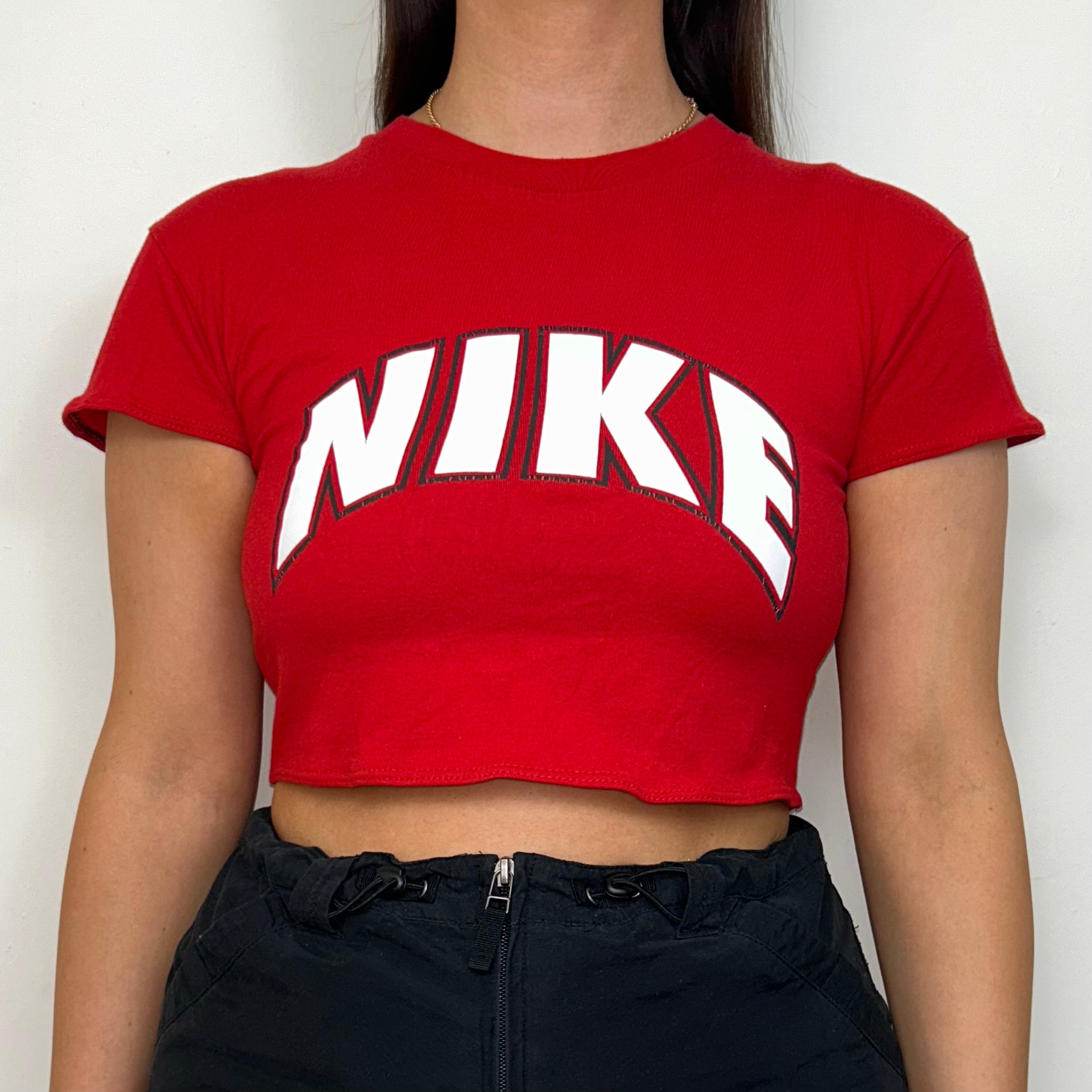 close up of red short sleeve crop top with white nike logo shown on a model wearing a black skirt