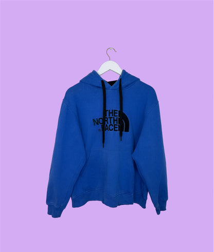 blue hoodie with black north face logo shown on a lilac background
