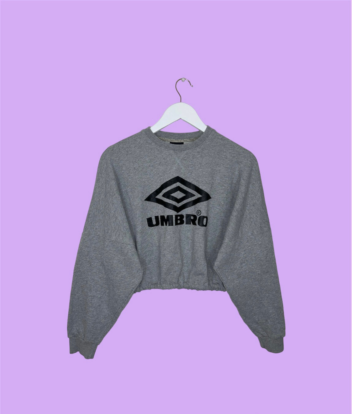 light grey cropped sweatshirt with black umbro logo shown on a lilac background