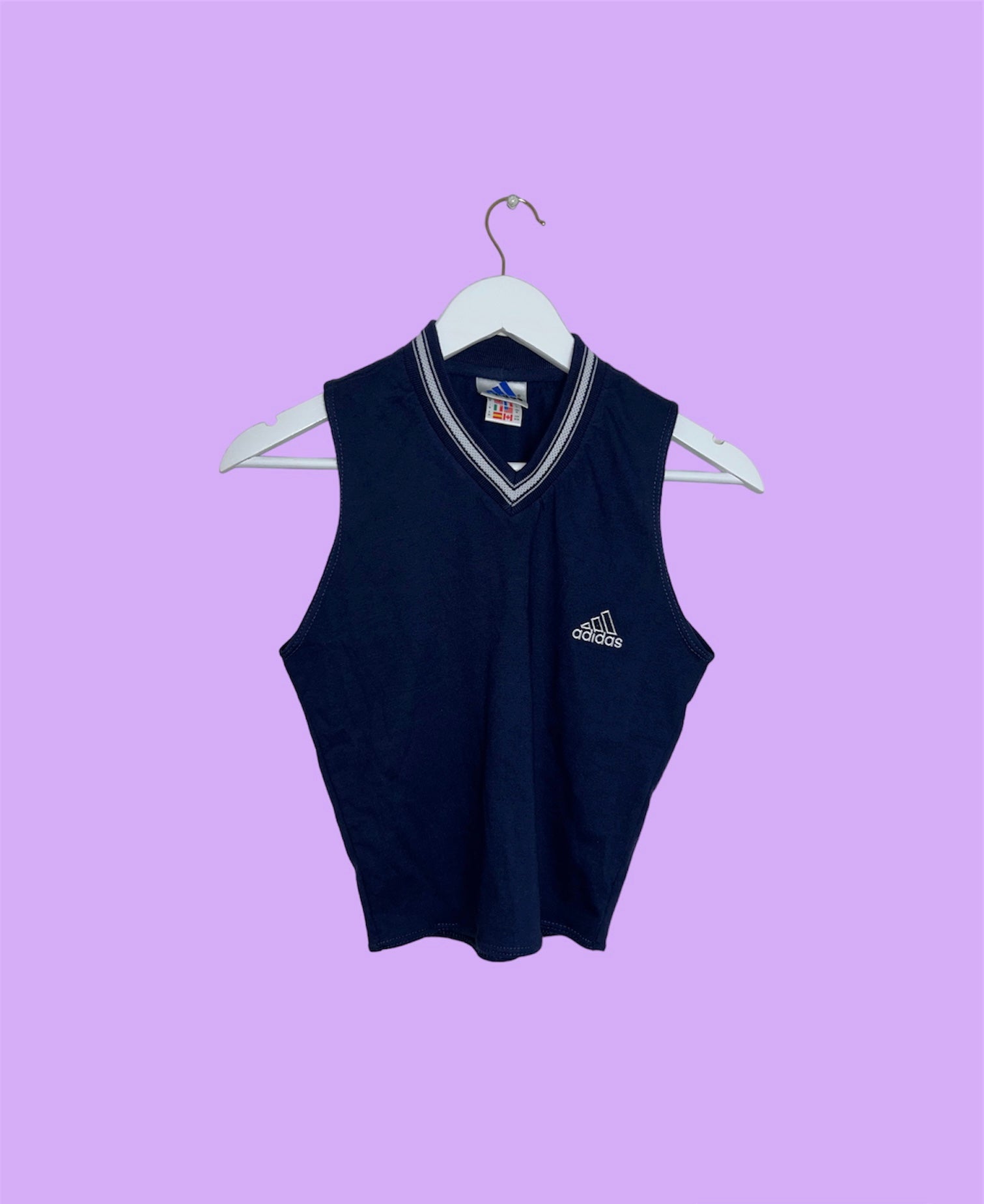 navy sleeveless crop top with white adidas logo shown on a lilac background