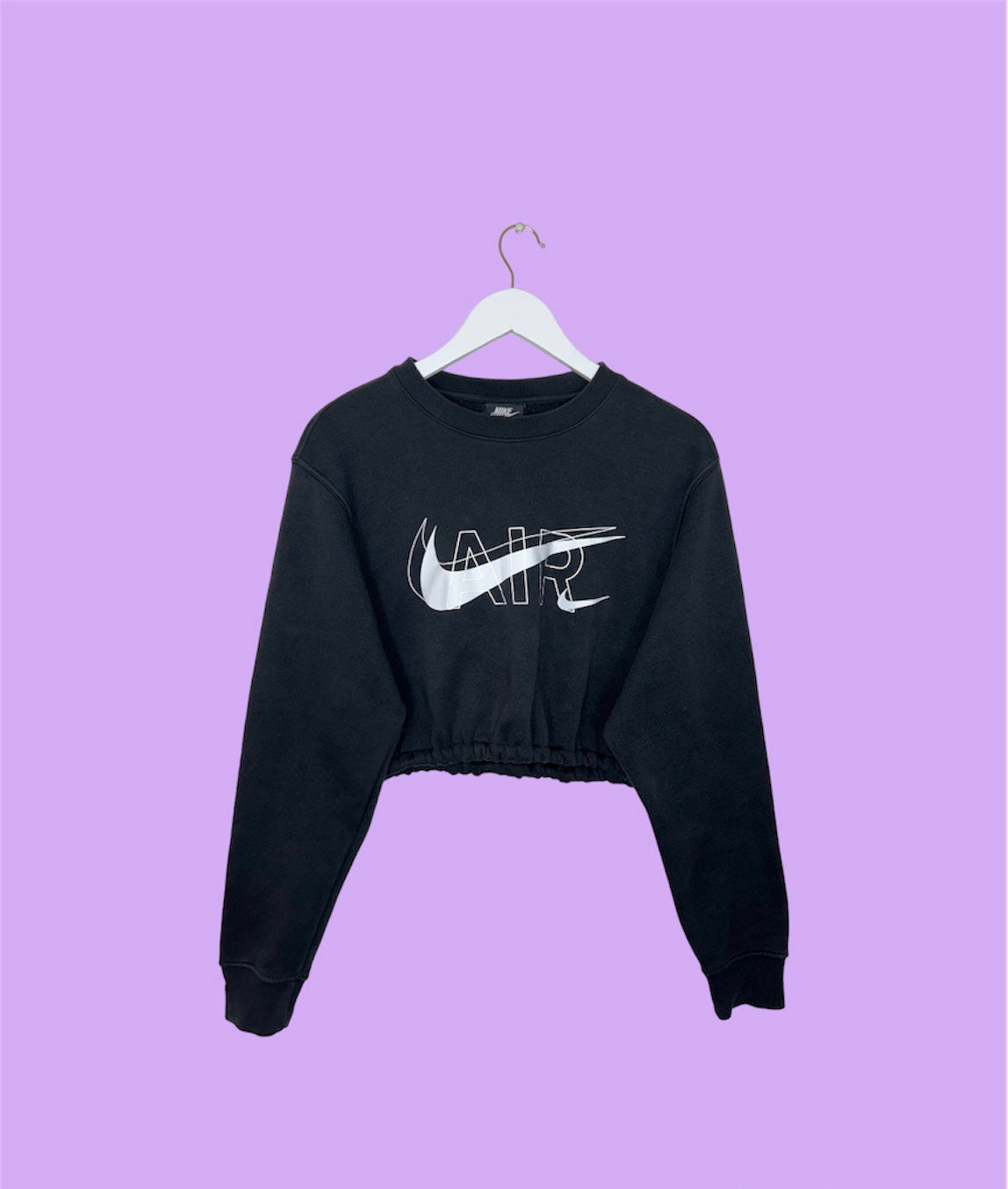 black cropped sweatshirt with white nike air logo shown on a lilac background