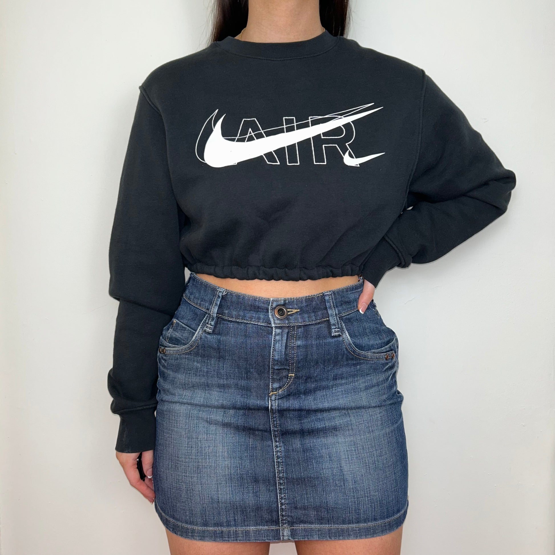 black cropped sweatshirt with white nike air logo shown on a model wearing a blue denim mini skirt