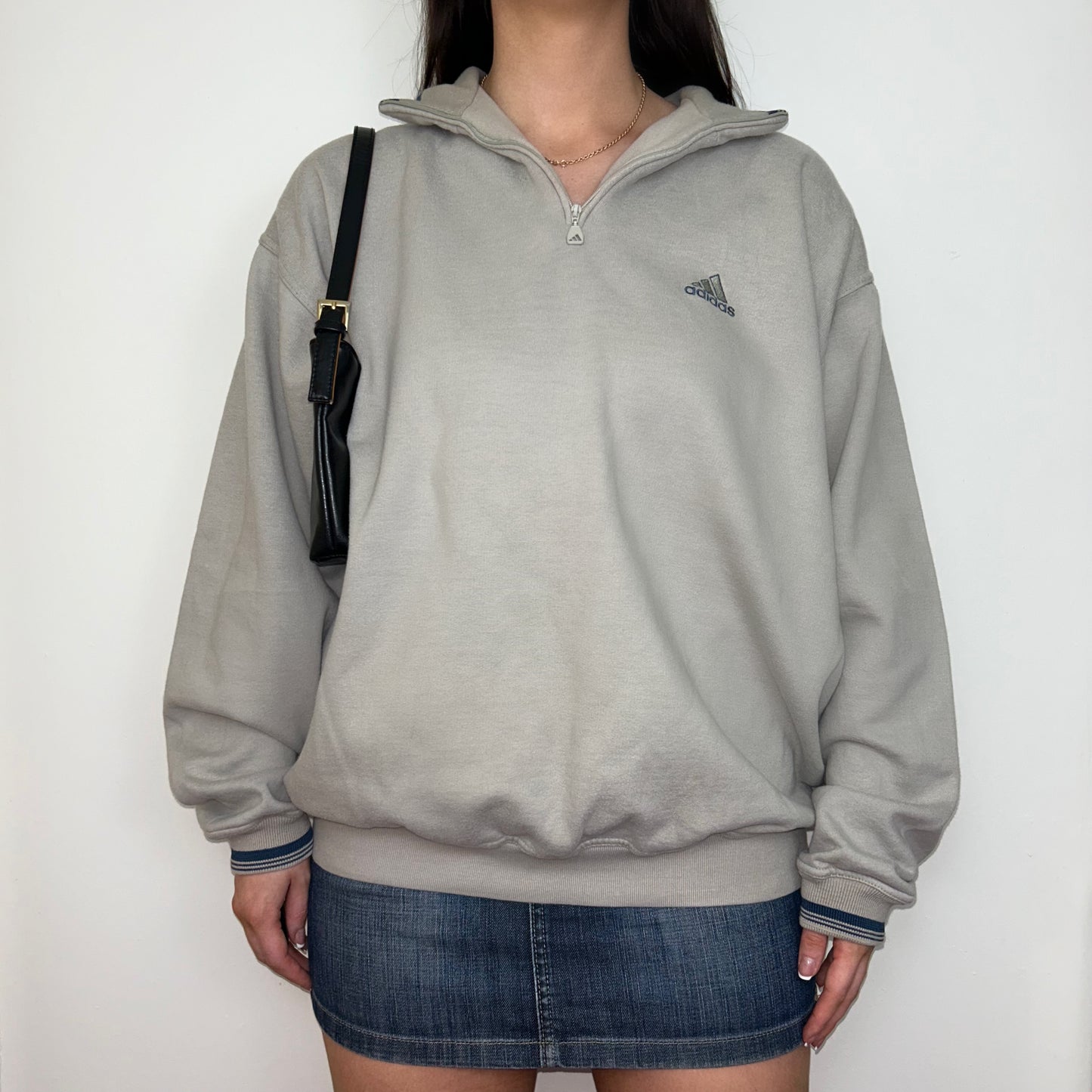 beige 1/4 zip sweatshirt with small adidas logo shown on a model wearing a blue denim skirt with a black shoulder bag