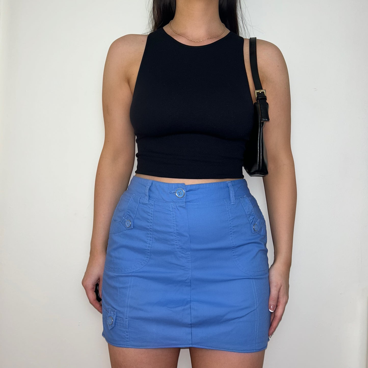 blue mini cargo skirt shown on a model wearing a black sleeveless crop top and black shoulder bag