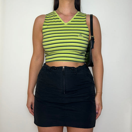 green and black sleeveless crop top with small adidas logo shown on a model wearing a black mini skirt and black shoulder bag