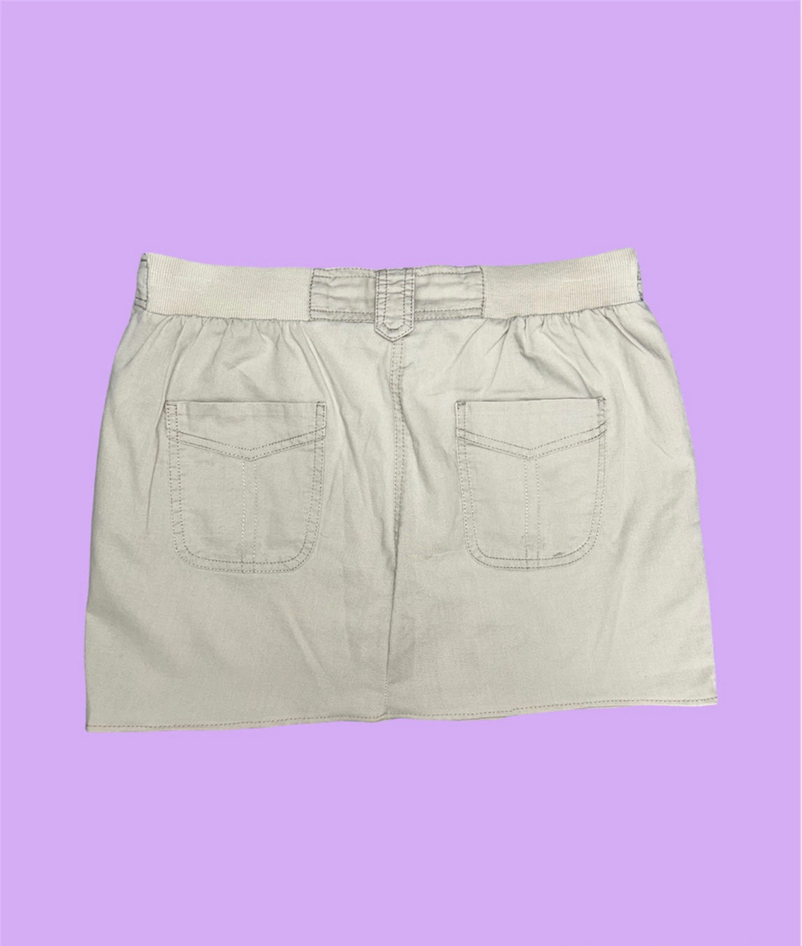 back of a beige cargo mini skirt shown on a lilac background