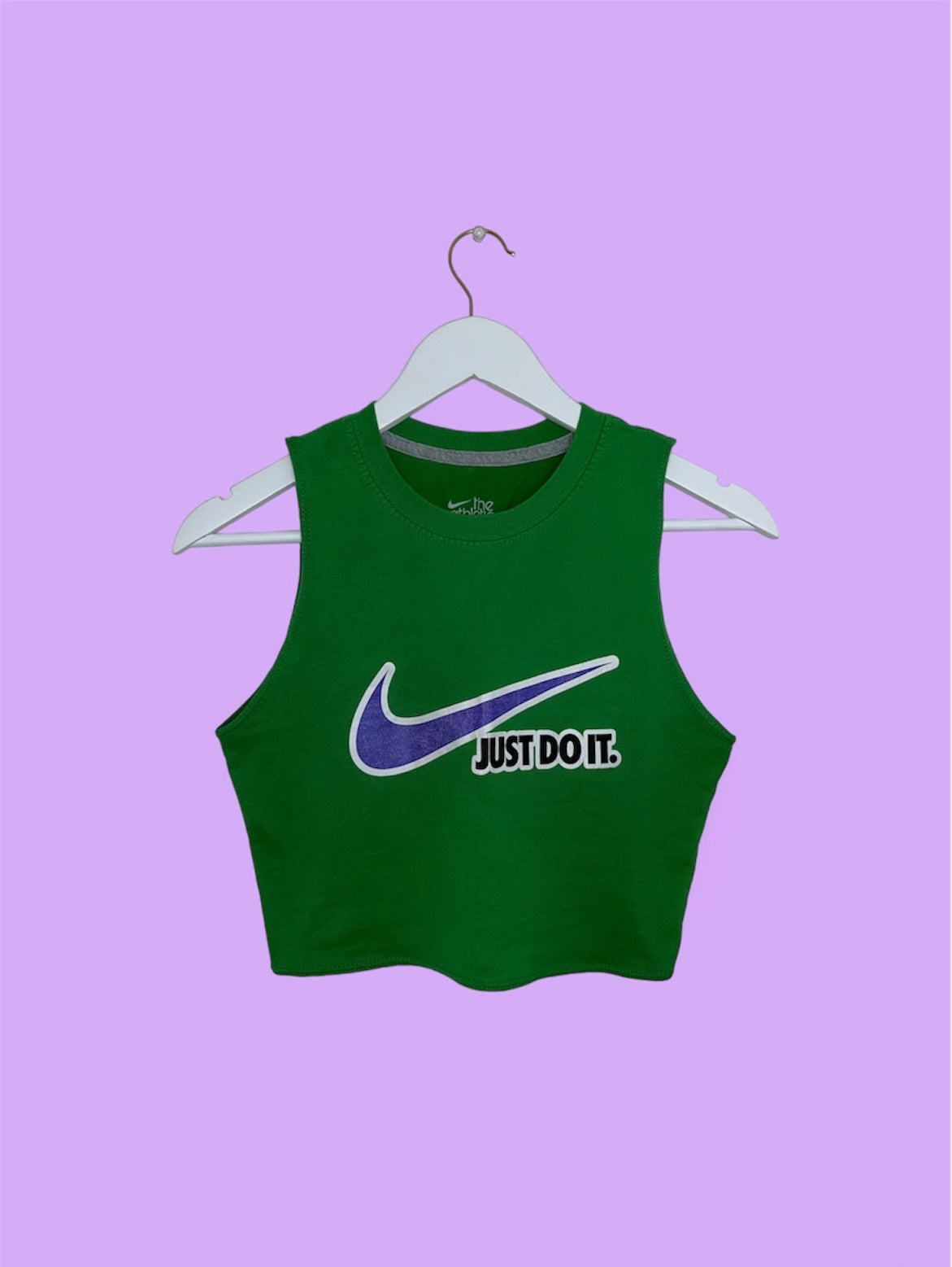 green sleeveless crop top with white and blue nike logo shown on a lilac background