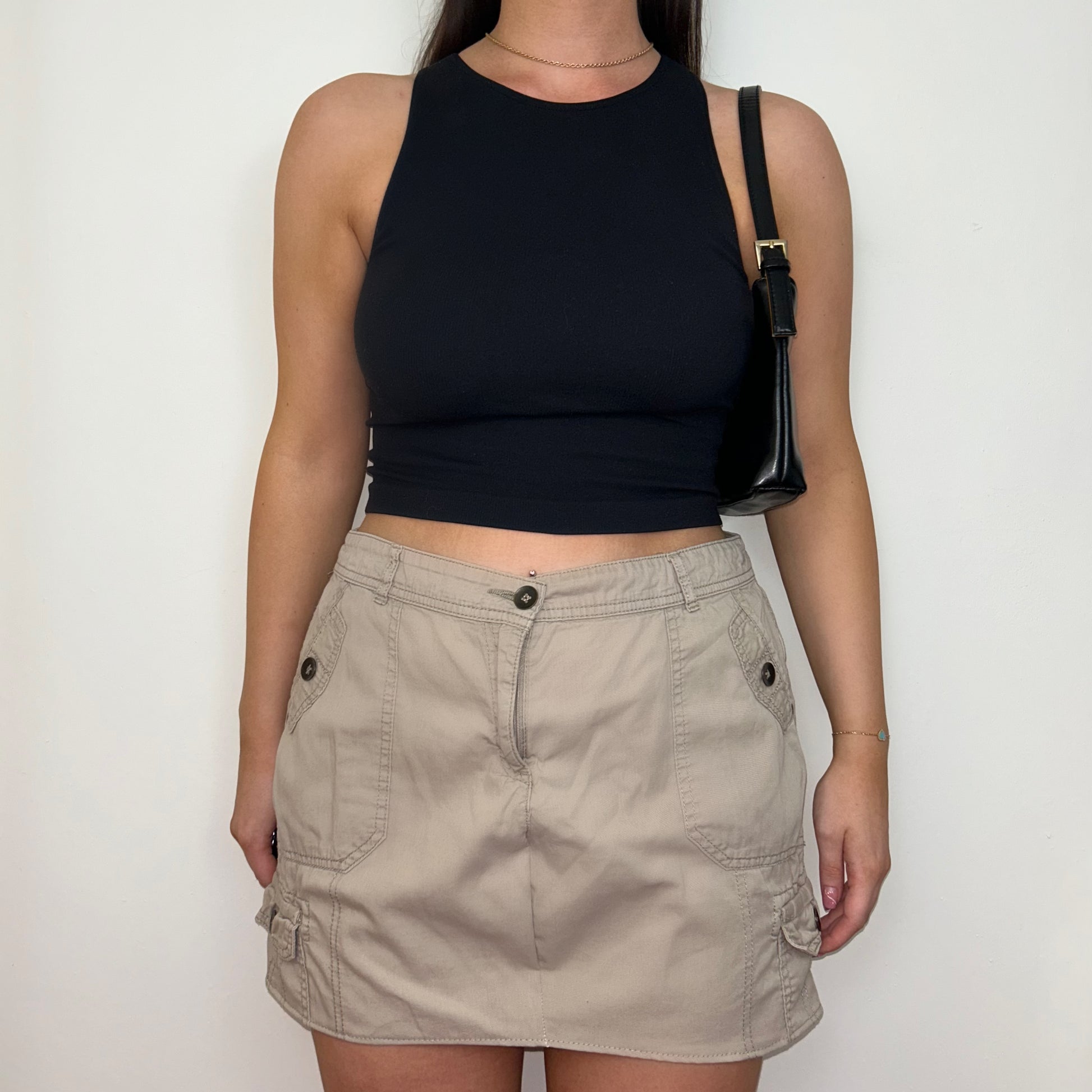 beige cargo mini skirt shown on a model wearing a black crop top and black shoulder bag