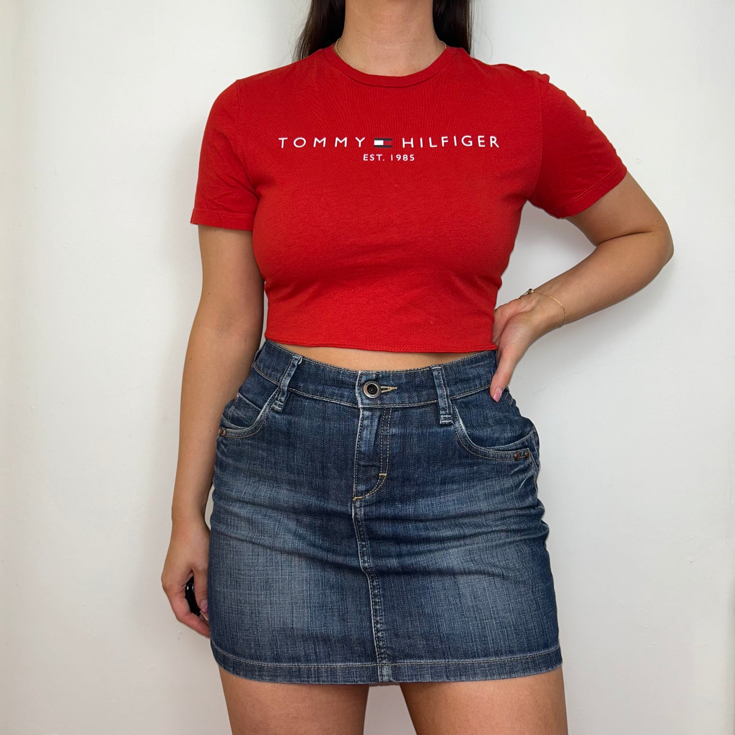 red short sleeve crop top with white tommy hilfiger logo shown on a model wearing a blue denim skirt