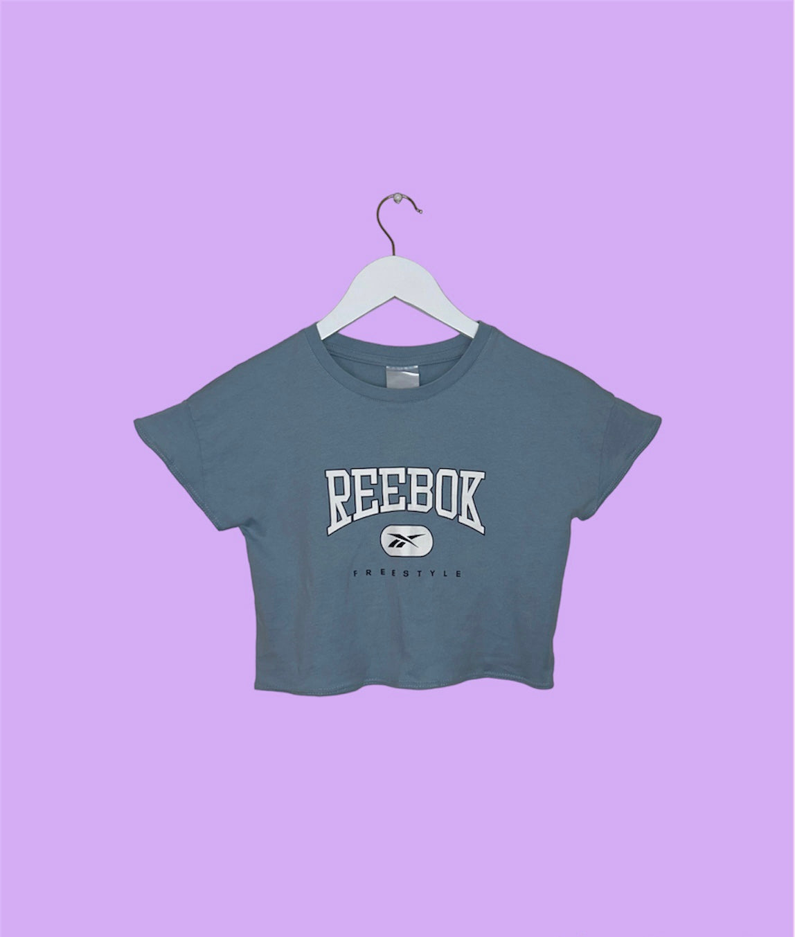 light blue short sleeve crop top with white reebok logo shown on a lilac background