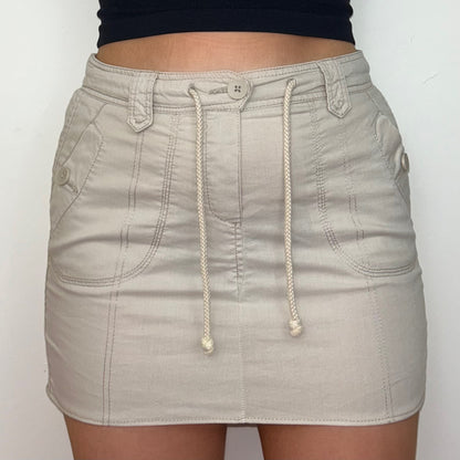 close up of beige cargo mini skirt shown on a model wearing a black crop top