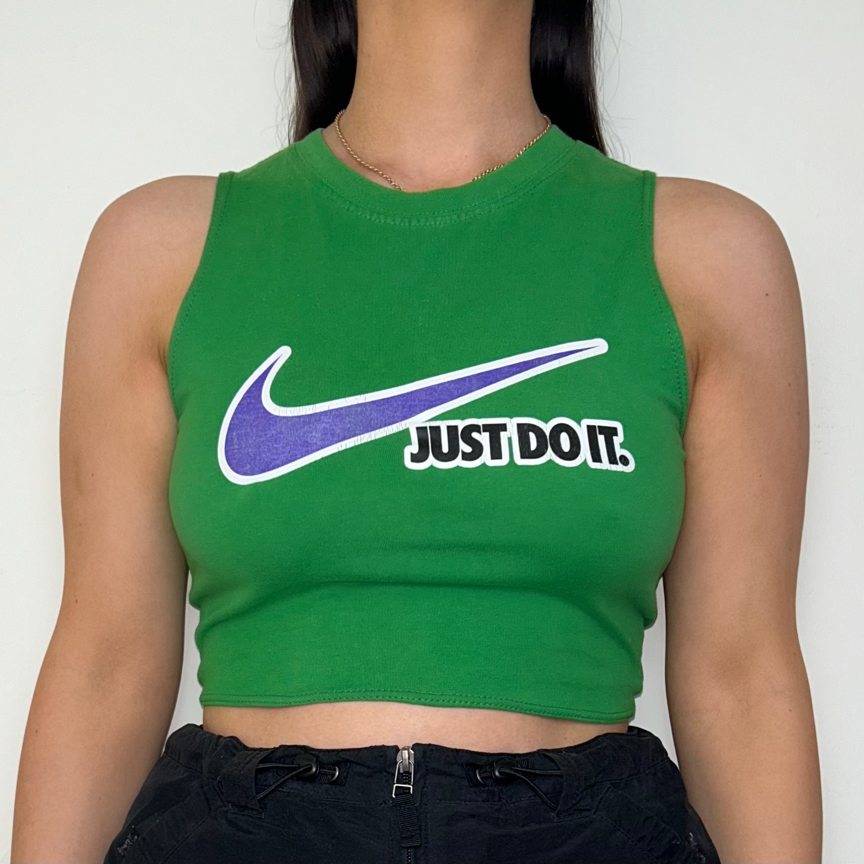 close up of green sleeveless crop top with white and blue nike logo shown on a model
