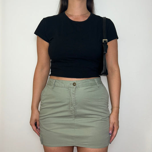 light green cargo mini skirt shown on a model wearing a short sleeve black crop top and black shoulder bag