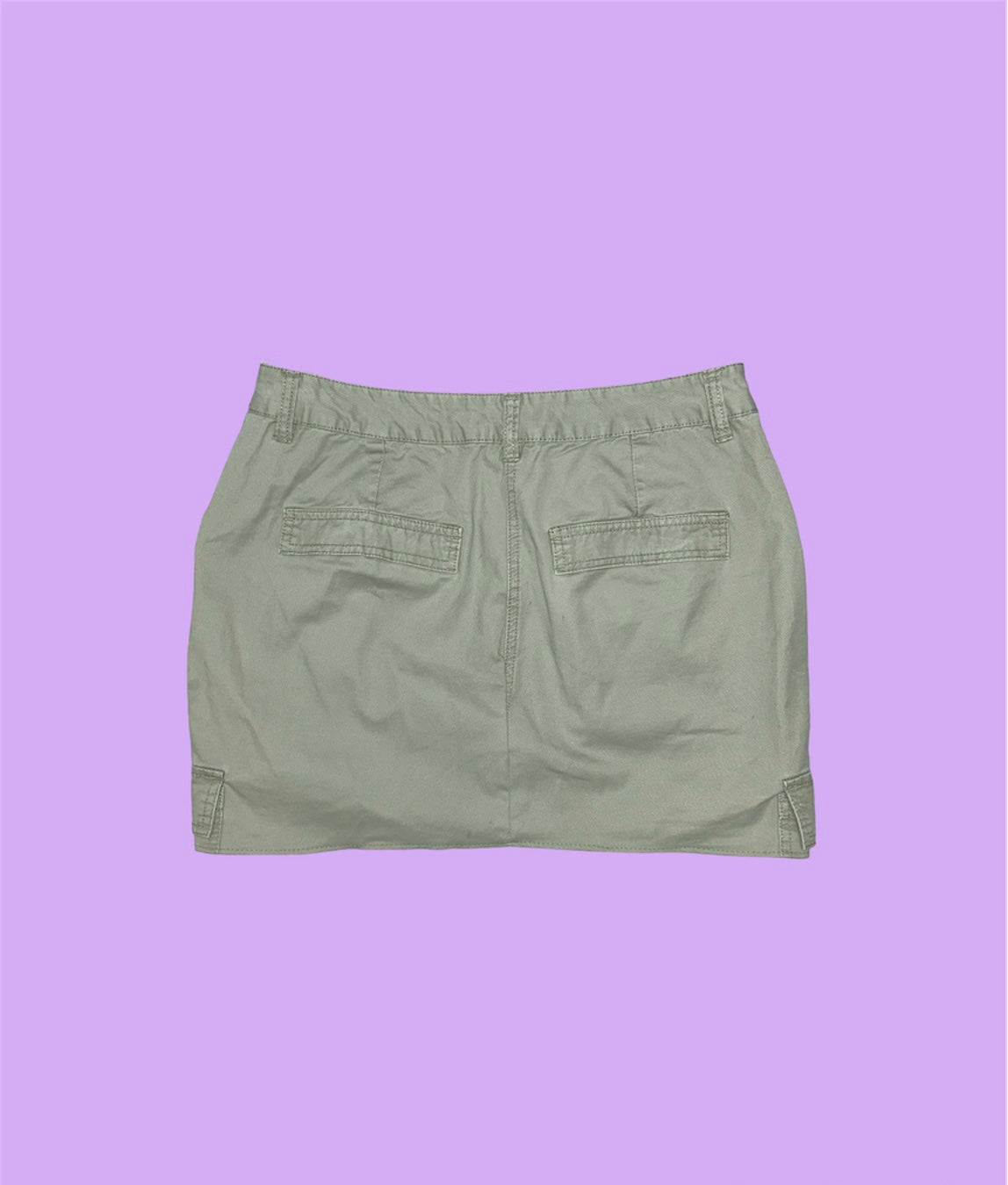 back of a light green cargo mini skirt shown on a lilac background