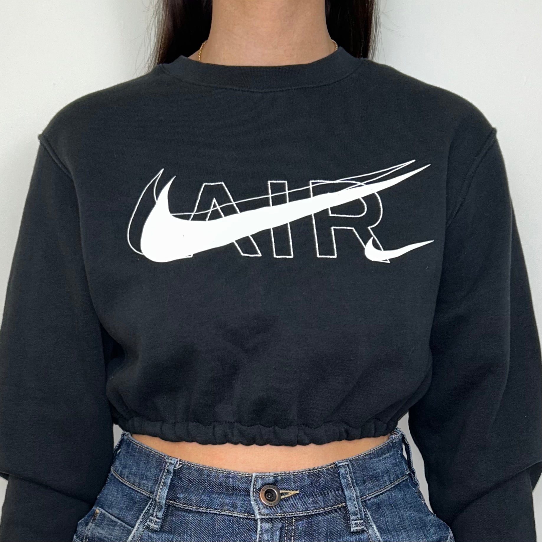 close up of black cropped sweatshirt with white nike air logo shown on a model