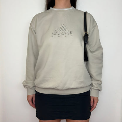 beige sweatshirt with adidas golf logo shown on a model wearing a black mini skirt and black shoulder bag