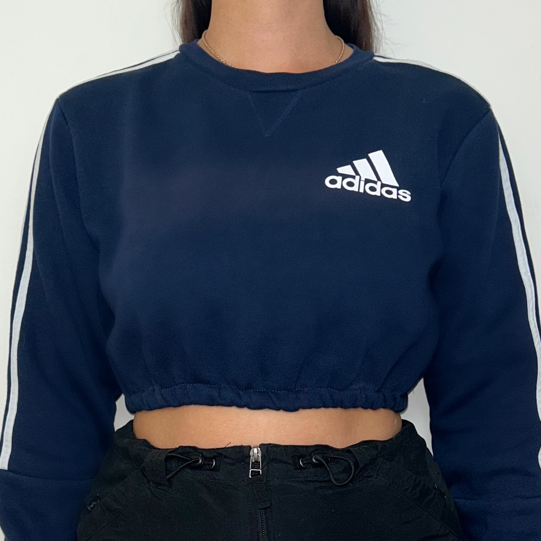 close up of navy cropped sweatshirt with white adidas logo shown on a model