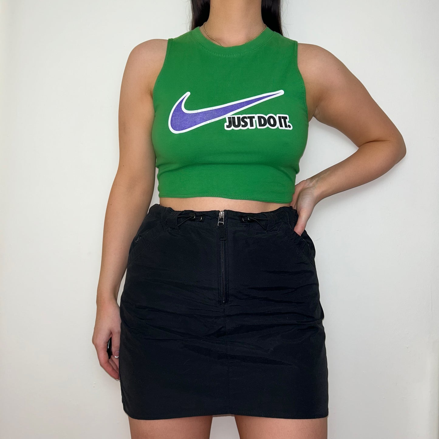 green sleeveless crop top with white and blue nike logo shown on a model wearing a black skirt