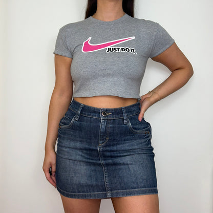 grey short sleeve crop top with pink nike swoosh logo shown on a model wearing a blue denim skirt