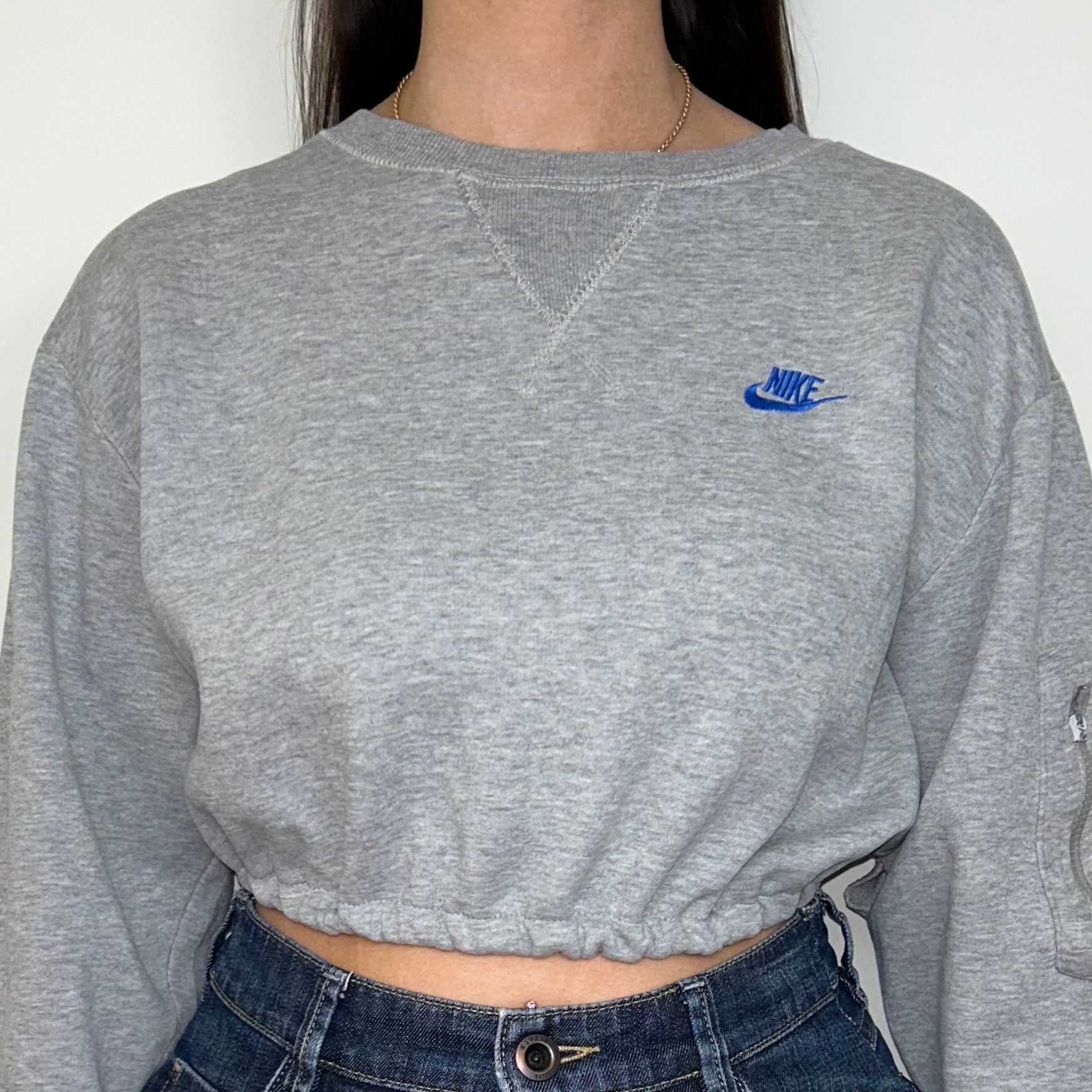 close up of grey cropped sweatshirt with blue nike logo shown on a model