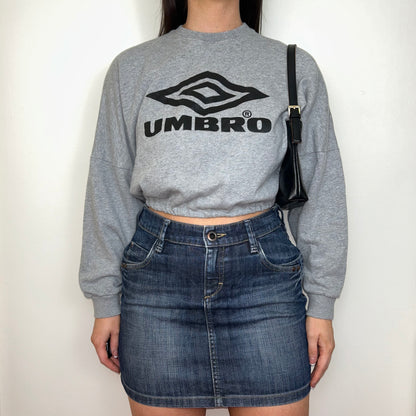 light grey cropped sweatshirt with black umbro logo shown on a model wearing a blue denim mini skirt and black shoulder bag