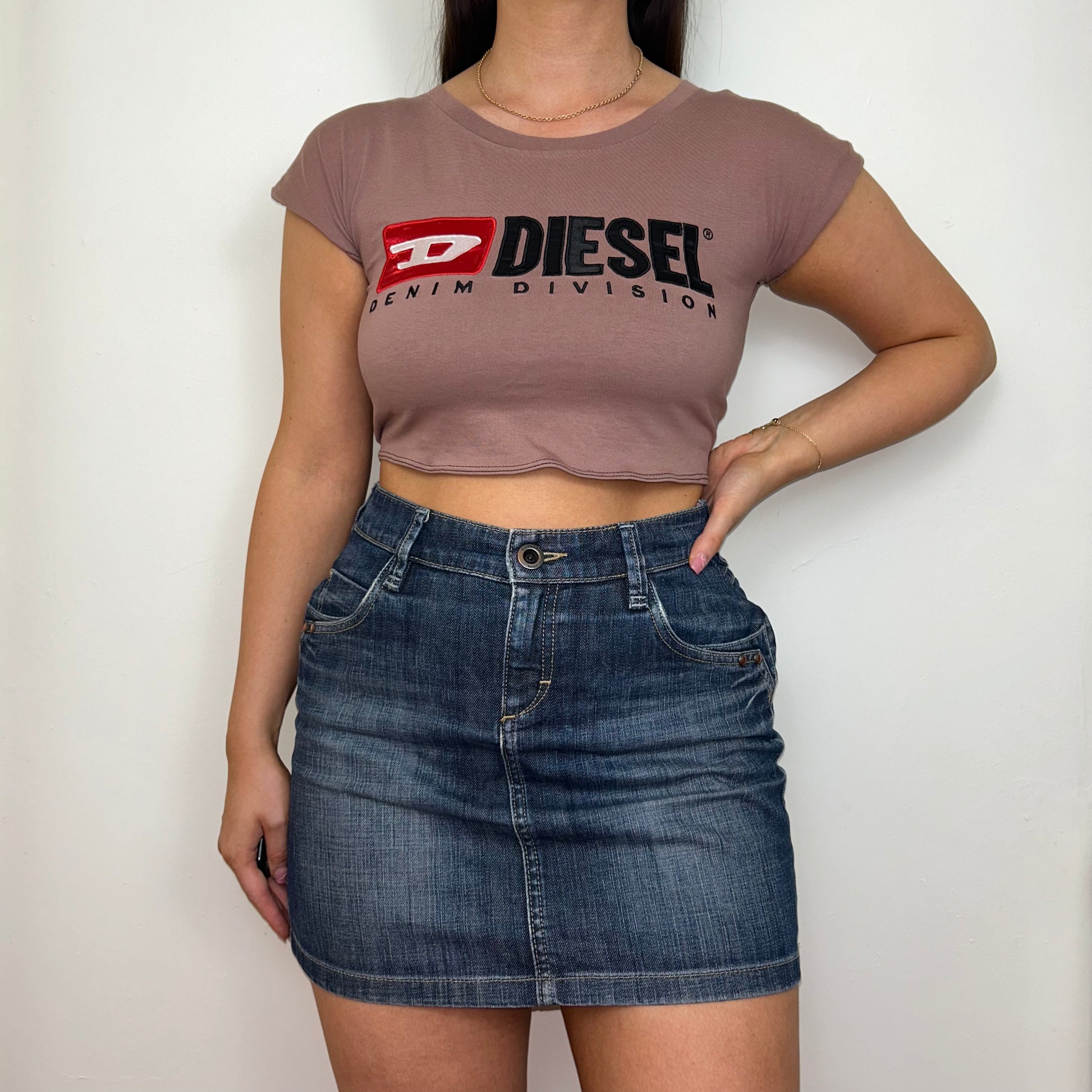 pink short sleeve crop top with black diesel logo shown on a model wearing a denim skirt