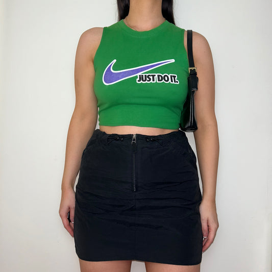 green sleeveless crop top with white and blue nike logo shown on a model wearing a black skirt and black shoulder bag