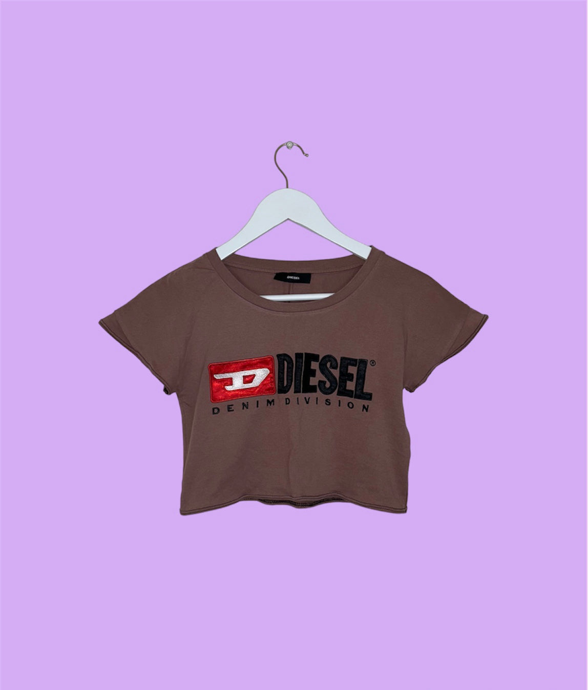 pink short sleeve crop top with black diesel logo shown on a lilac background