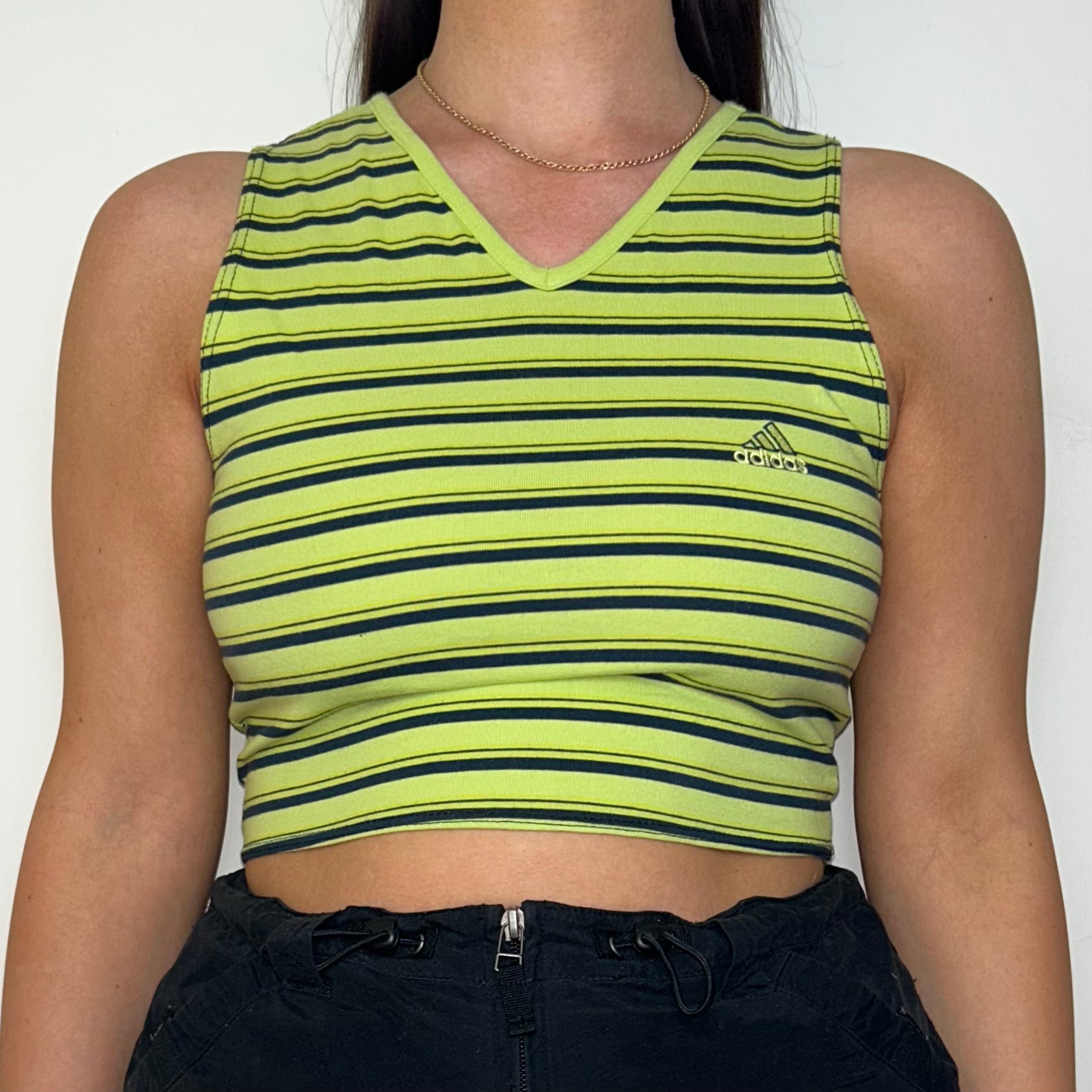 green and black sleeveless crop top with small adidas logo shown on a model