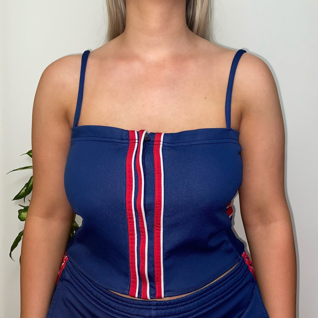 close up of model wearing blue and red strappy corset top with 3 red stripes and matching skirt