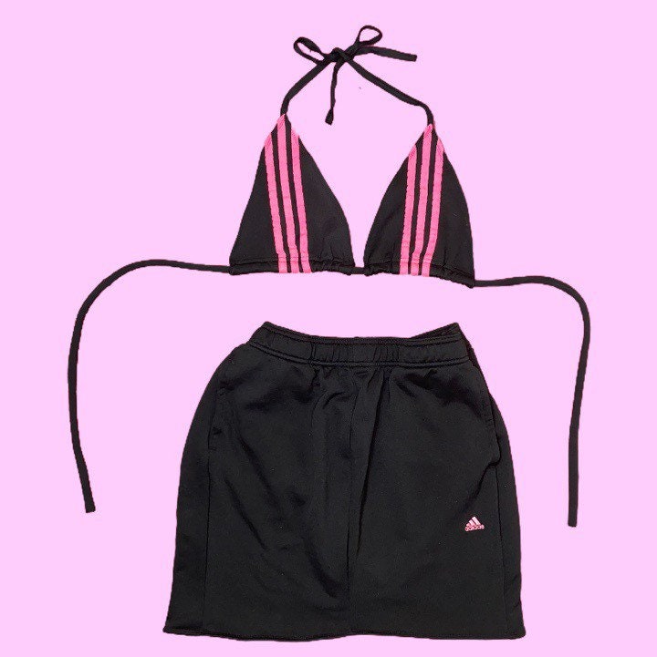 Adidas bikini crop top hot pink 3 stripe detail and matching black skirt with small pink Adidas logo on a light pink background