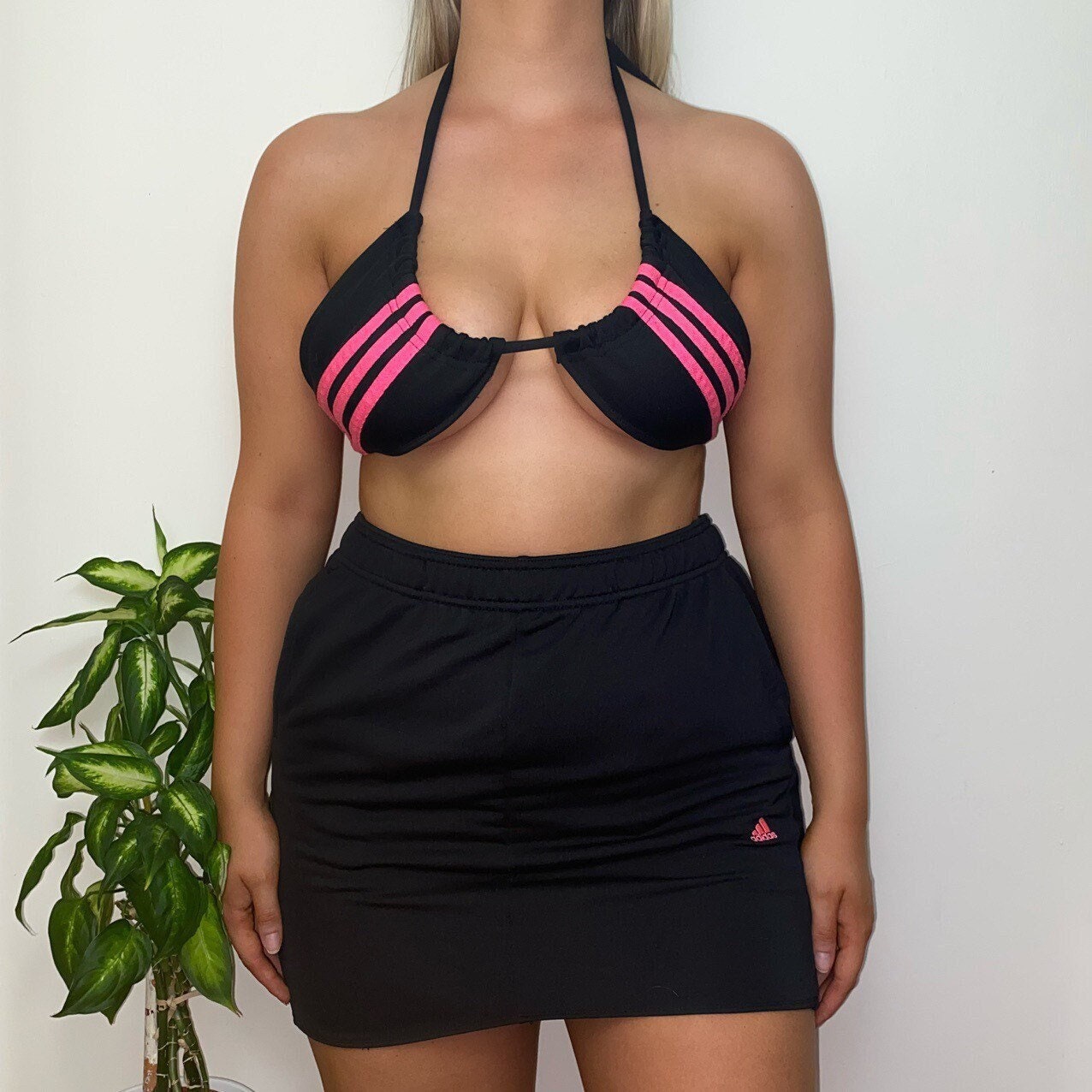 model wearing adidas bikini crop top with hot pink 3 stripe detail and matching black skirt with small pink adidas logo