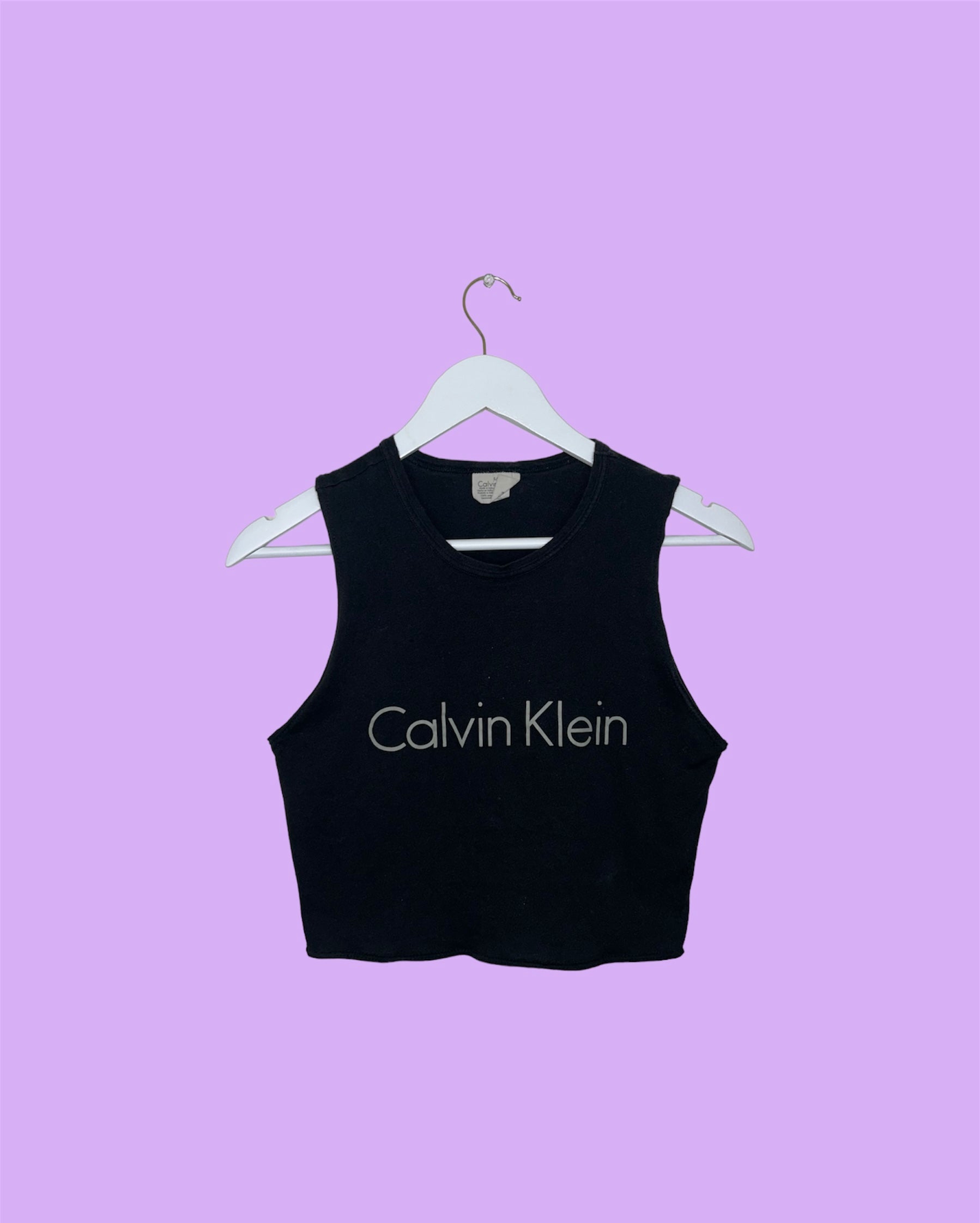 black sleeveless crop top with grey calvin klein logo on a lilac background