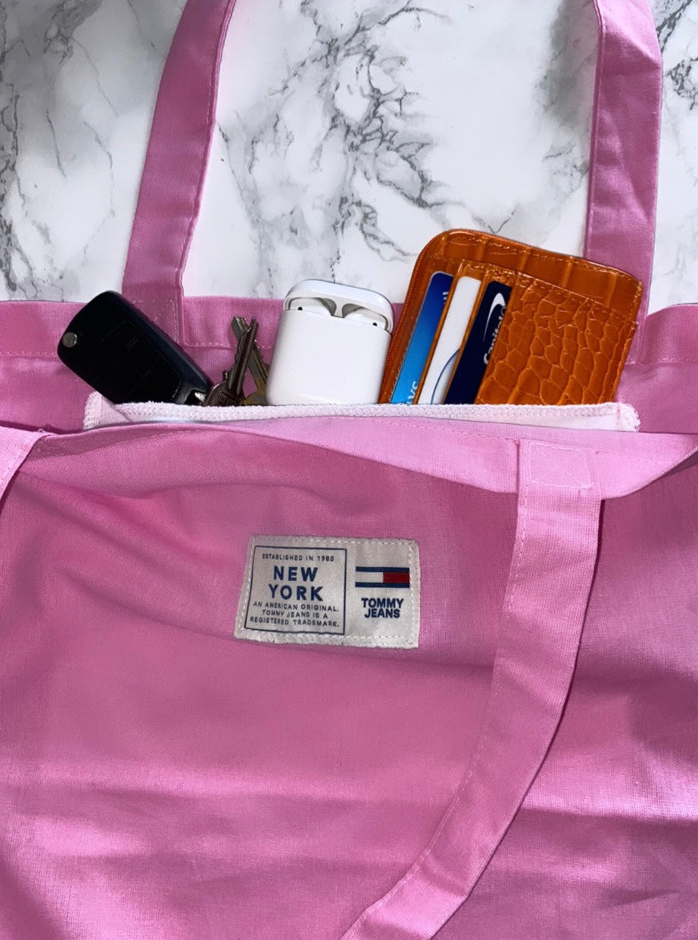 light pink tote bag with tommy jeans logo with keys, airpods and wallet in pocket