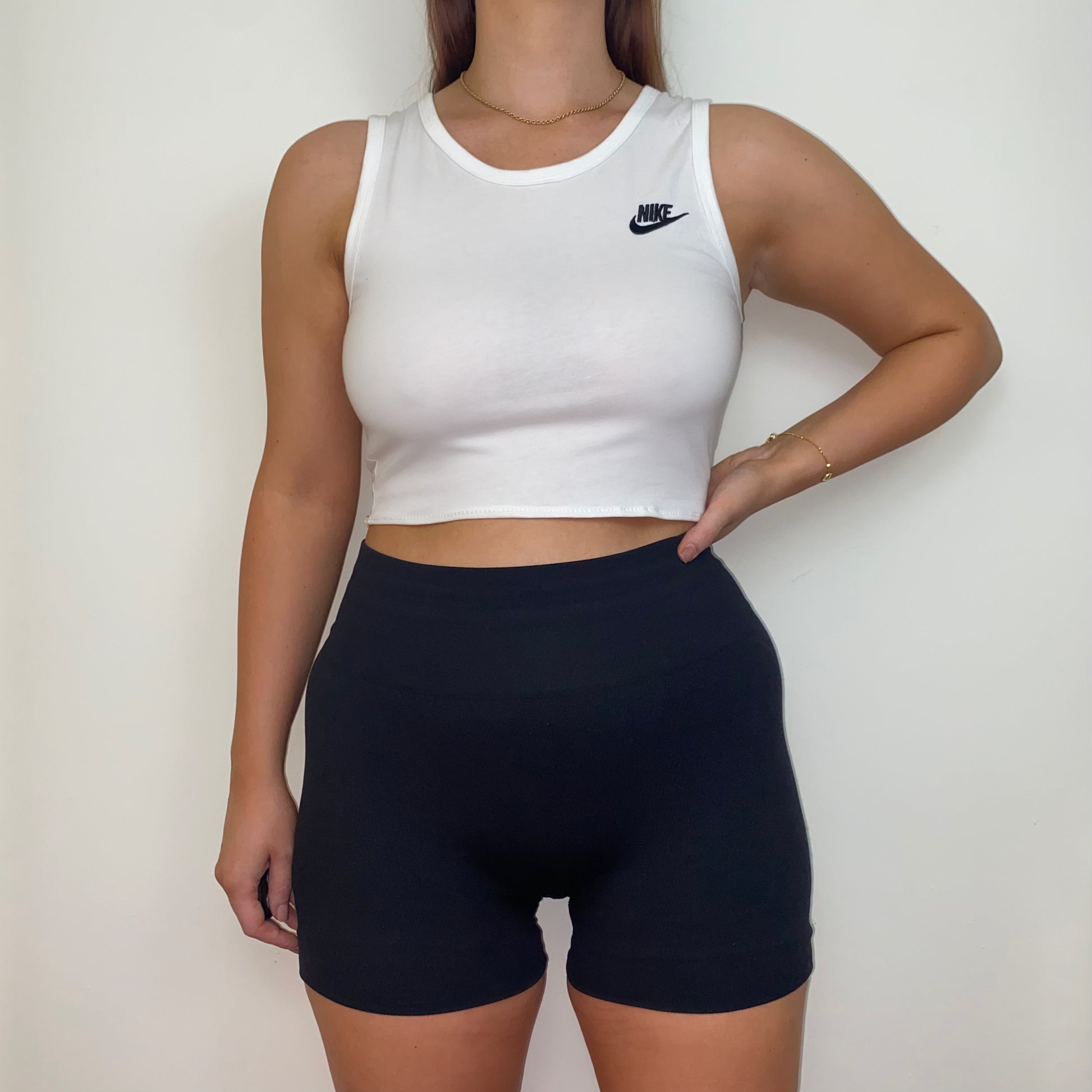 white short sleeve crop top with black nike logo shown on a model wearing black shorts