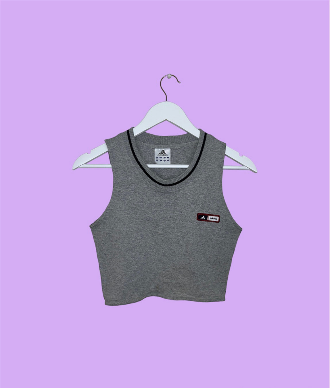 grey sleeveless crop top with small adidas logo shown on a lilac background