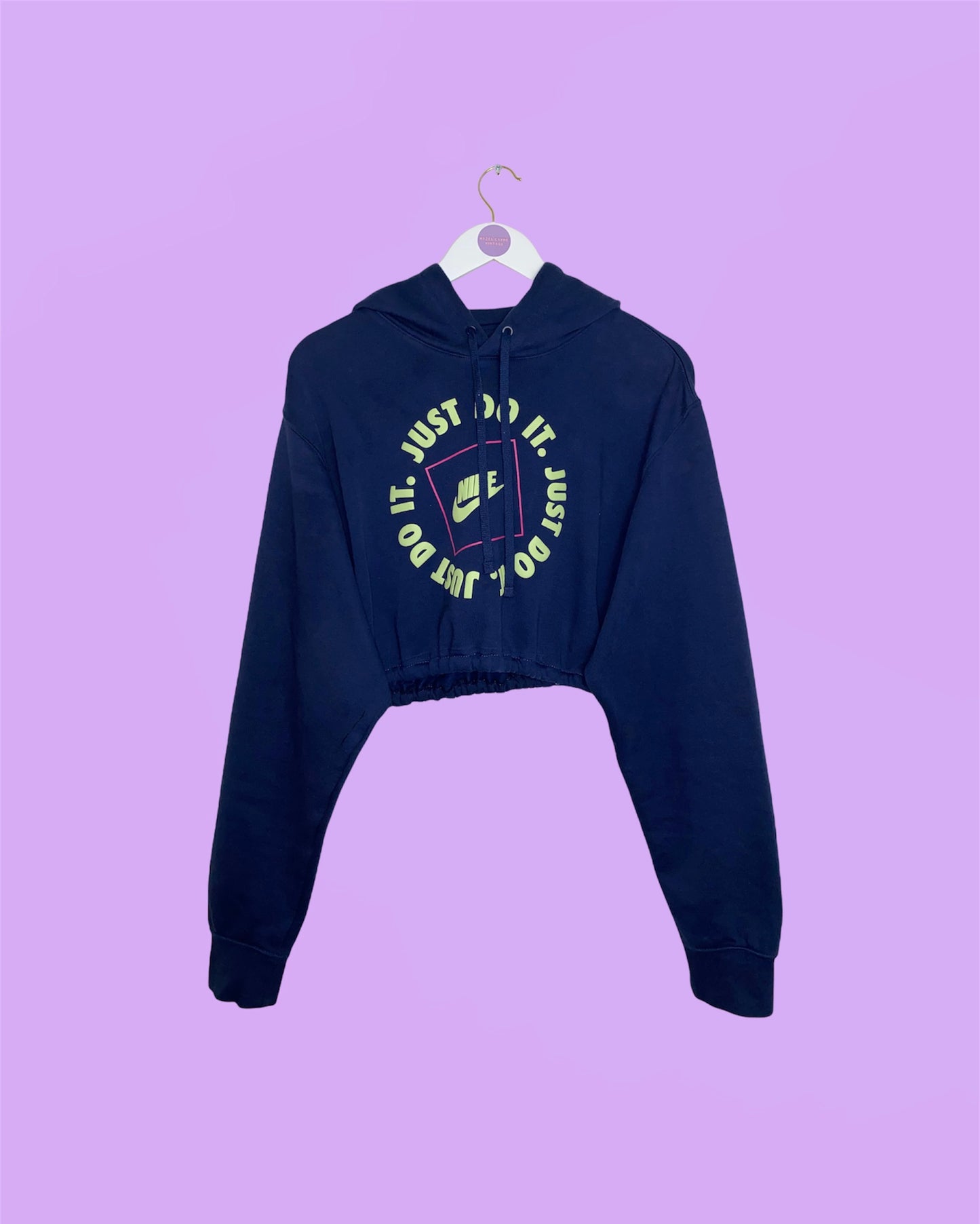 navy cropped hoodie with yellow print nike text shown on a white clothes hanger on a lilac background