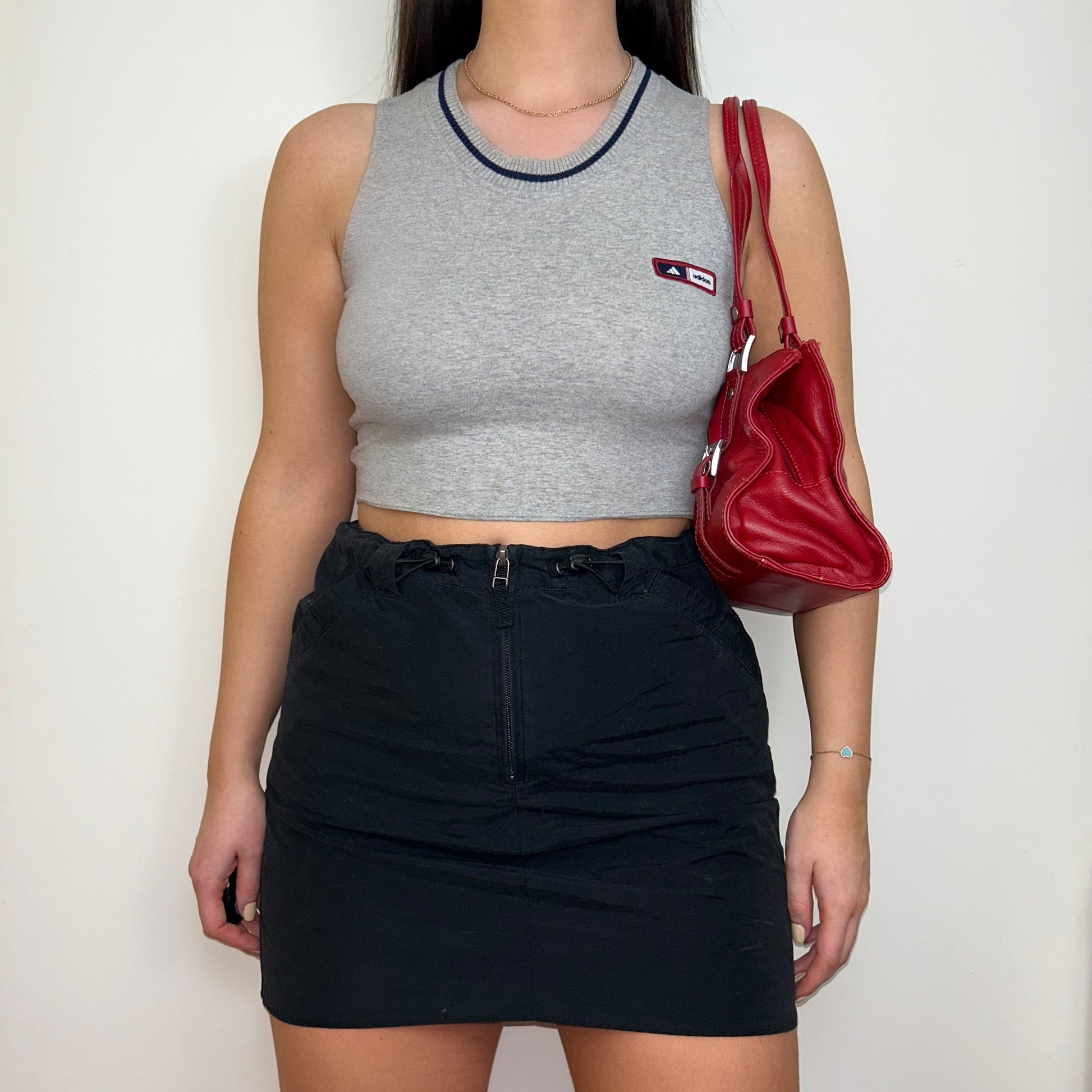 grey sleeveless crop top with small adidas logo shown on a model wearing a black mini skirt and red shoulder bag