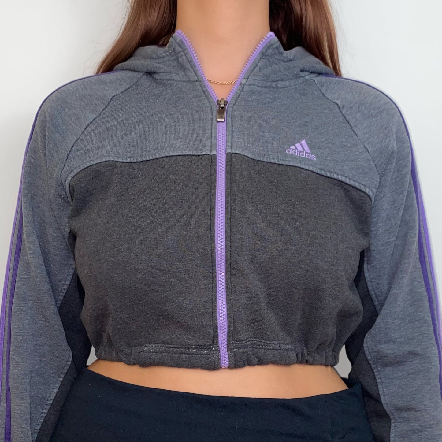 close up of grey and purple 1/4 zip cropped hoodie with purple adidas logo shown on a model wearing a black skirt