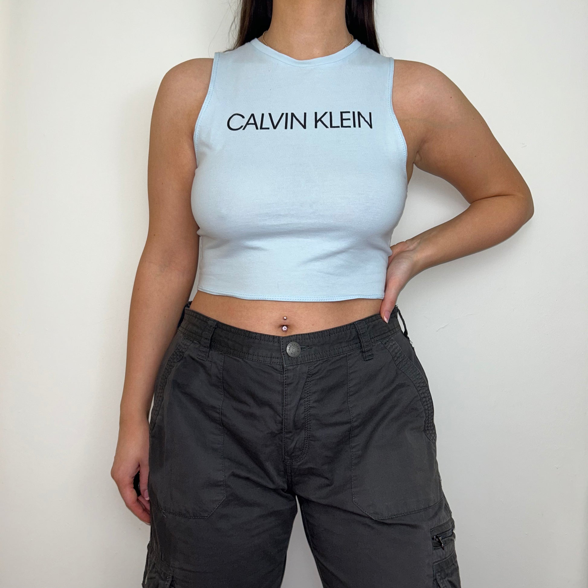 baby blue sleeveless crop top with black calvin klein logo shown on a model wearing grey cargo trousers