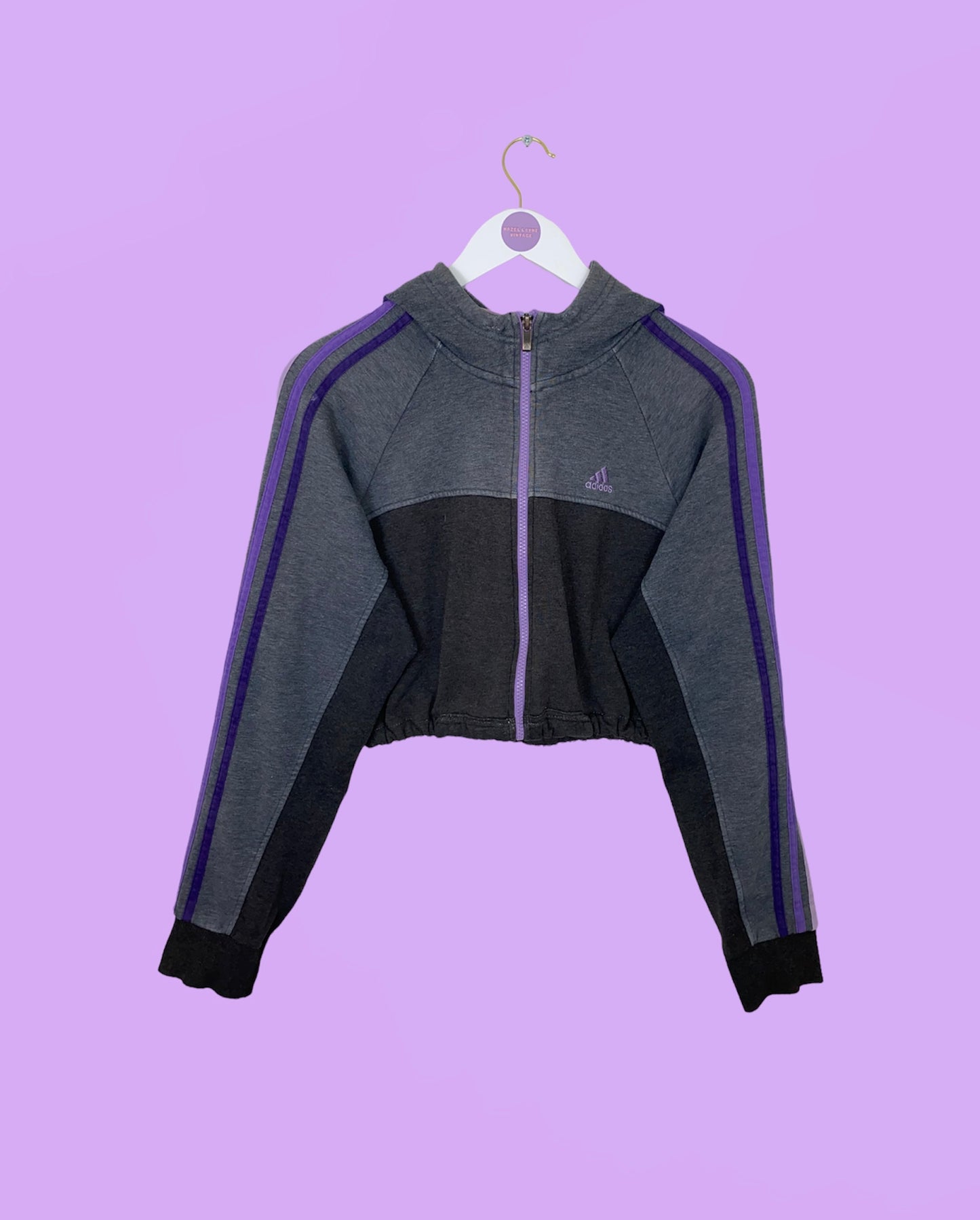 grey and purple 1/4 zip cropped hoodie with purple adidas logo shown on a white clothes hanger on a lilac background