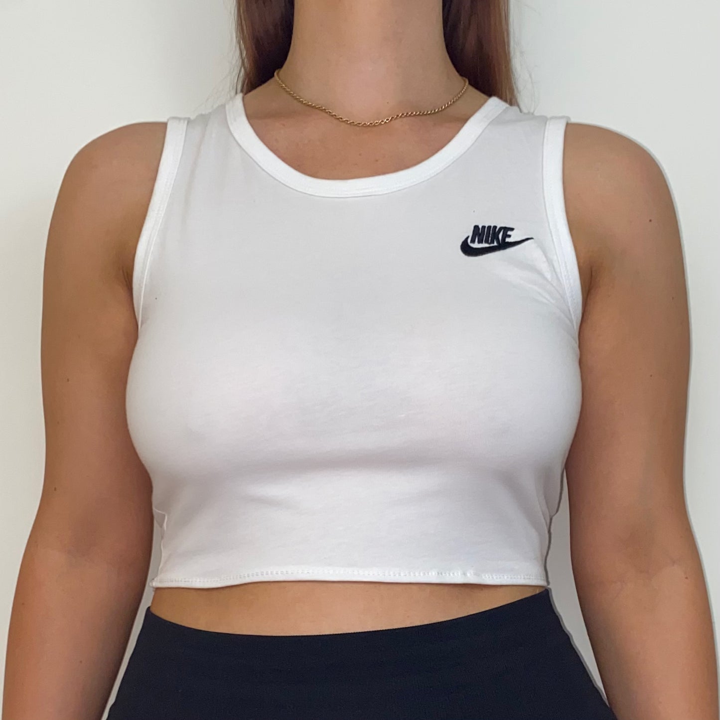 close up of white short sleeve crop top with black nike logo shown on a model