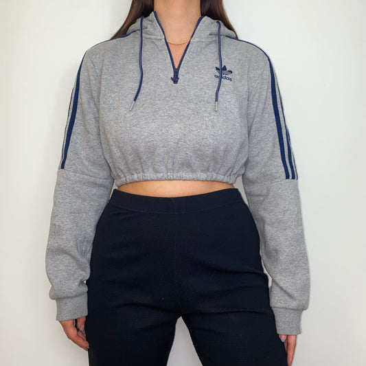 grey 1/4 zip cropped hoodie with navy adidas logo shown on a model wearing black trousers