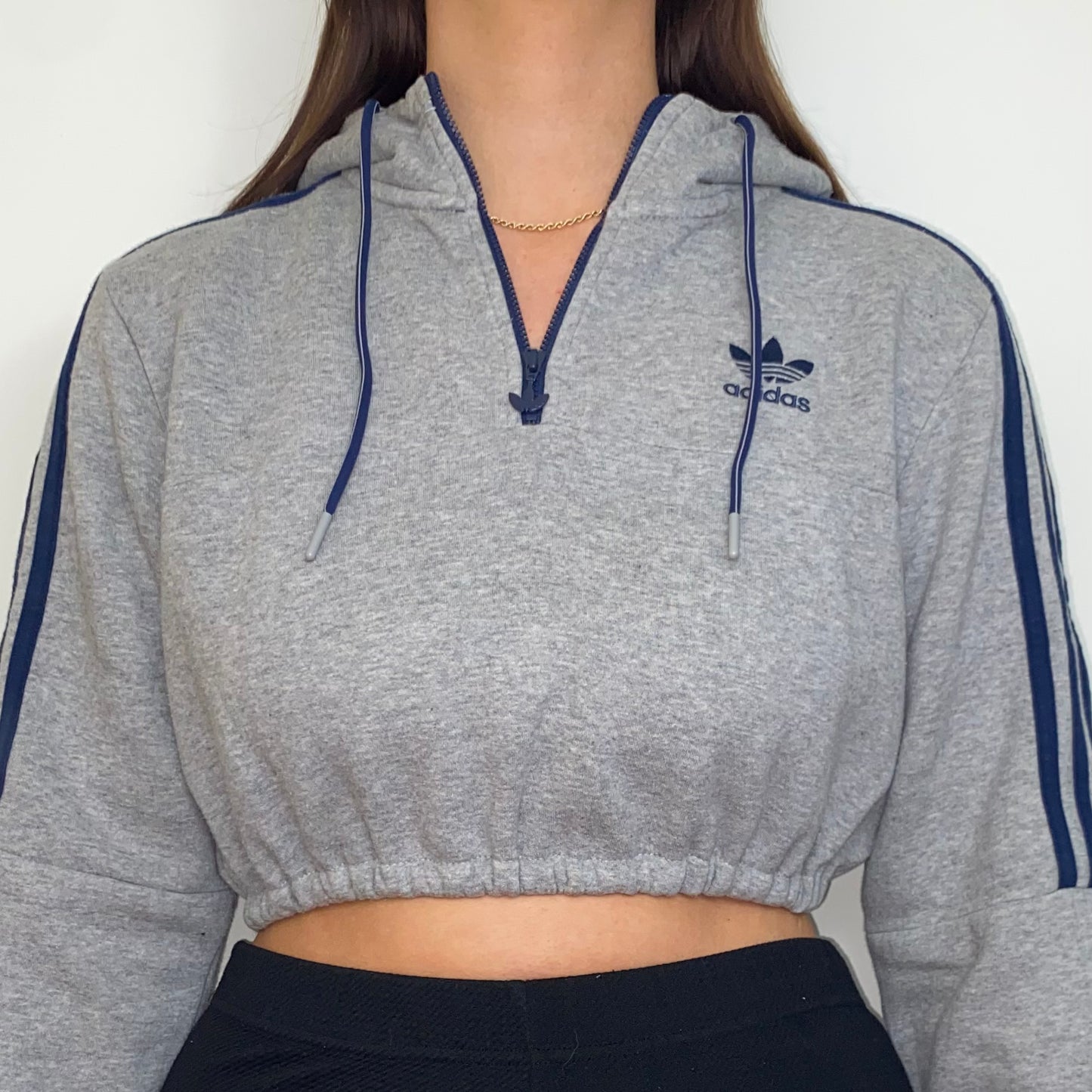 close up of grey 1/4 zip cropped hoodie with navy adidas logo shown on a model
