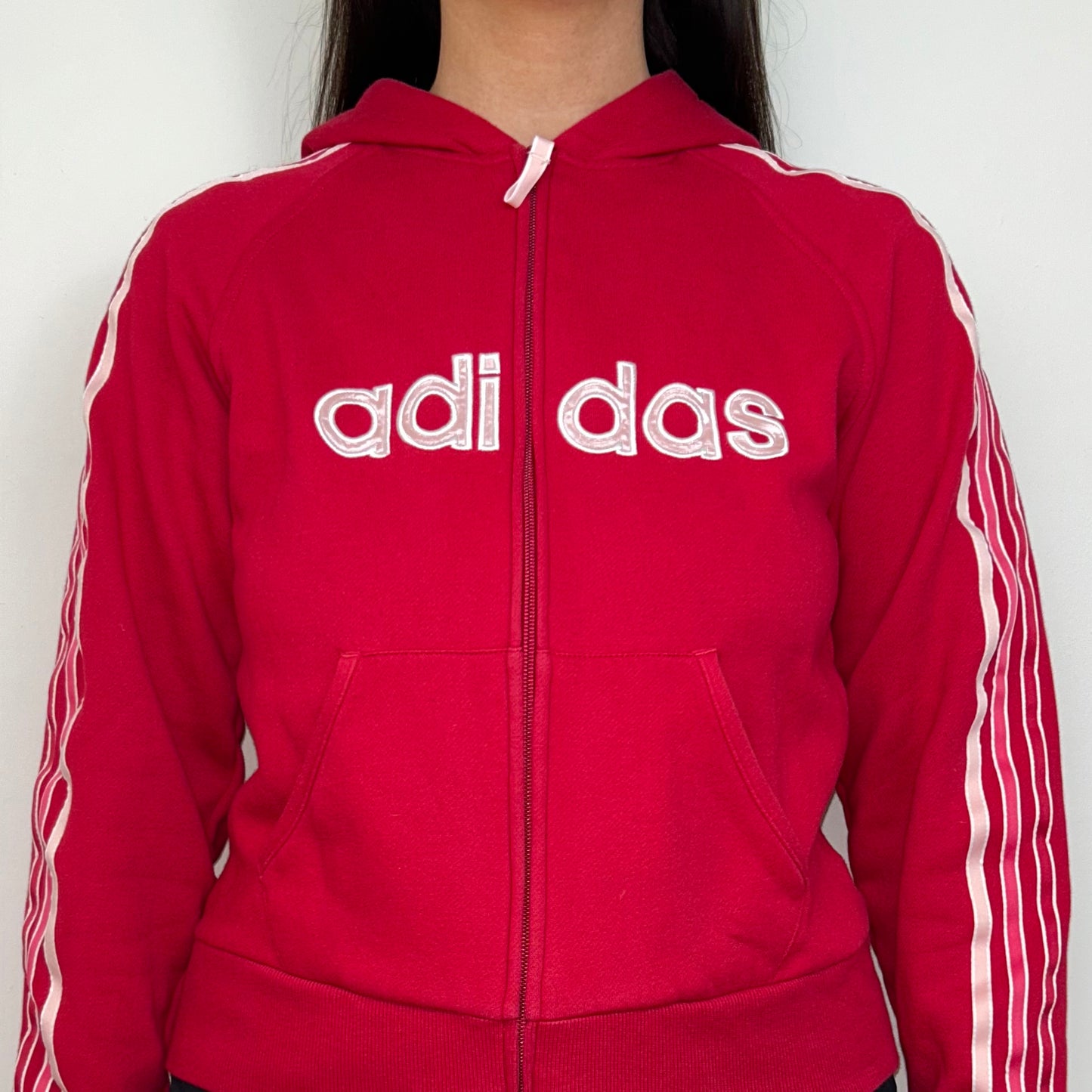 close up of red zip up hoodie with big adidas text logo shown on a model