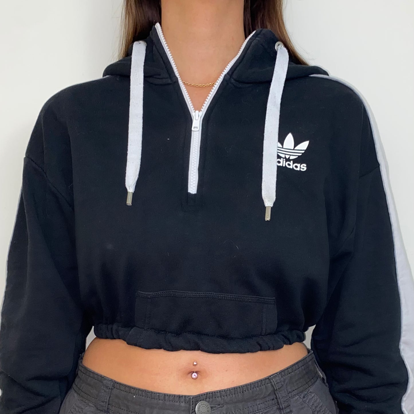 close up of black 1/4 zip cropped hoodie with white adidas logo shown on a model